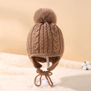 Detailed cable knit pattern on camel winter hat with fluffy faux fur pom and earflaps