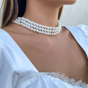 Detailed view of triple-layer faux pearl choker with gold vertical spacer bars