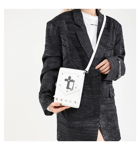 Detail of white cross messenger bag with silver star studs on a stylish black suit