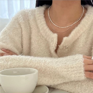 Close-up of double-layered sterling silver necklace on a model in knitwear