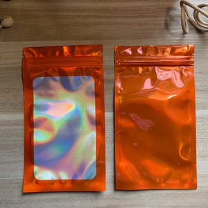 Detail of orange holographic zip lock bags with clear window on a wooden background