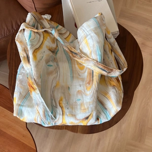 Macro view of artistic marble print canvas tote bag with simple wish label on wooden table
