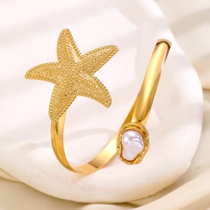 Close-up of gold starfish and irregular pearl detail on the adjustable arm cuff