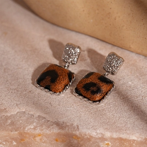 Macro detail of silver square leopard print earrings with hammered metal texture