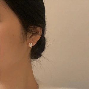 Close-up of elegant flower stud earring with white petals and gold center on ear