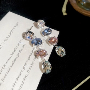 Makroaufnahme von Silber-Ohrhängern mit bunten ovalen Edelsteinen in Krallenfassung