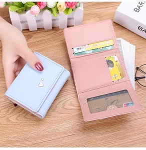 Detail view of pink and blue trifold wallets showing interior card slots and heart metal decor