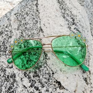 Close-up of kids aviator sunglasses with green lenses and daisy flower enamel detail