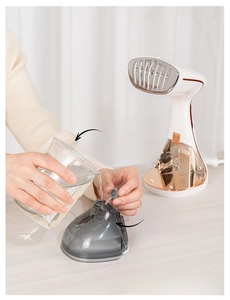 Close-up of filling the detachable water tank of a handheld white and gold garment steamer