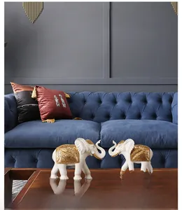 Detail view of white and gold elephant resin statues on a dark wooden table in living room