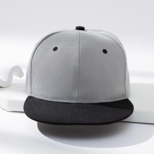 Neutral grey and black flat brim snapback hat displayed on a modern minimalist platform