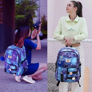 Detail view of purple galaxy print backpack with blue pom-pom charm and decorative badge