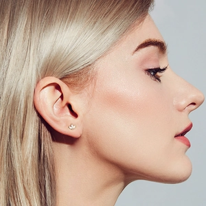 Close-up of golden marquise stud earring with sparkling cubic zirconia on a model ear