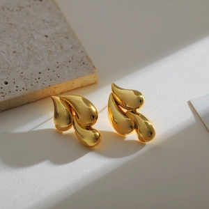 Polished 18K gold double teardrop earrings on textured stone base