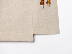 Detail of linen fabric with beaded drawstring showing natural texture and stitching