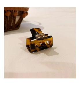 Detailed view of leopard tortoiseshell acetate hair claw with gold spring on a neutral background