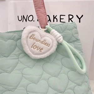 Detail of quilted heart pattern mint bag with plush heart charm and rope handle