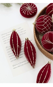 Détail de boules de Noël floquées rouge foncé avec motifs pailletés dorés sur un plateau