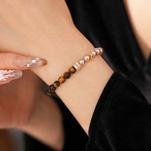 Detailed shot of tiger eye stone and pearl beaded bracelet with gold zircon spacers