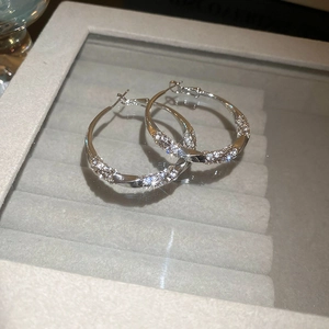 Macro shot of silver twisted hoop earrings with micro-pave crystals on velvet