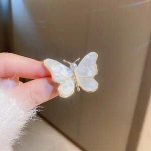 Vue macro détaillée d'une broche papillon plaquée or avec perle et éclats étincelants