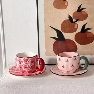 Detail of red rose and pink floral hand-painted ceramic coffee cup and saucer set