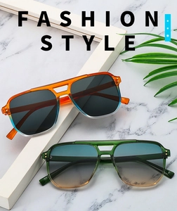 Detail of oversized double-bridge aviator sunglasses with gradient lenses on marble