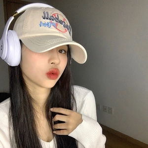 Beige cotton baseball cap with blue and red embroidery worn by a model in a studio