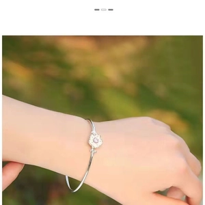 Detail of silver cherry blossom cuff bracelet with a pink gemstone on a wrist