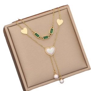 Double-layered gold necklace featuring a green gemstone and white heart pearl pendants