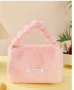 Detail of pink plush cosmetic bag with fluffy texture and unique beaded handle design