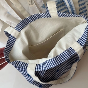 Internal view of blue striped canvas tote showing storage pocket and cotton lining