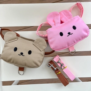 Detalle de mochilas para mascotas de oso y conejo con correas a juego sobre un banco