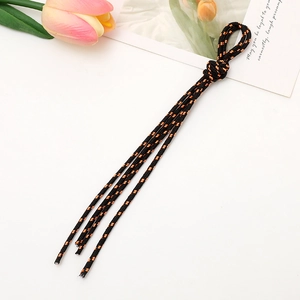 Detail of black woven phone strap with orange dots, knotted top, and tassel fringe accent