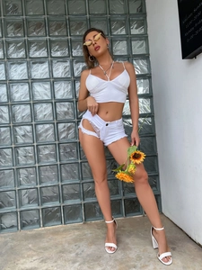 Dettaglio degli shorts in denim bianco con design traforato e orlo sfrangiato su modella