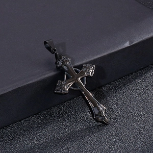 Detailansicht eines schwarzen Metallkreuz-Anhängers mit Mustern auf einer edlen Textur