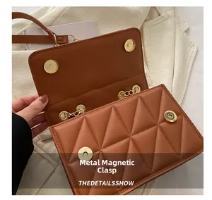 Detail of caramel quilted bag featuring magnetic metal buckle and golden chain strap