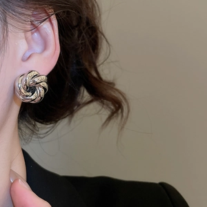 Close-up of a silver spiral knot earring featuring a polished metallic finish on a model