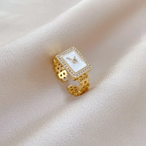 Macro shot of gold watch-style ring with zircon bezel and white shell dial detail