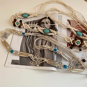 Detail of bohemian hand-woven belts featuring turquoise, wood beads and metal butterfly charms