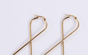 Close-up of golden figure-eight earrings showing polished finish and hinge details
