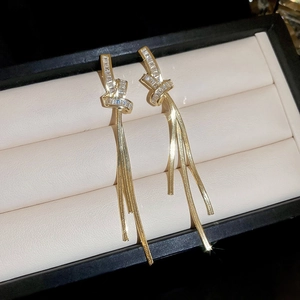 Detailed close-up of gold plated knot tassel earrings with sparkling zircon inlay