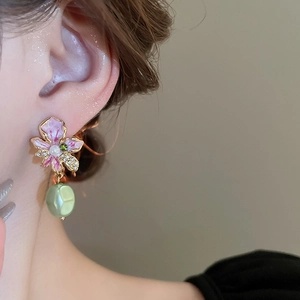 Close-up of vintage gold floral earrings with pink enamel, white pearls and green beads