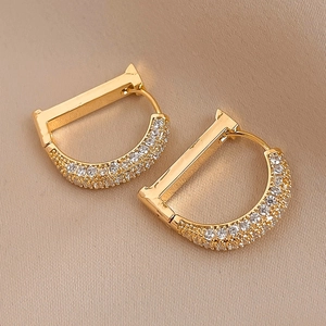 Macro shot of gold-plated D-letter earrings with pavé-set zircons on silk background