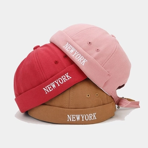 Détail de trois bonnets docker en coton avec broderie blanche NEW YORK en rose rouge et brun