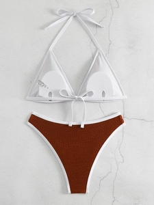Flachbild von weißem Neckholder-Bikinioberteil und rostrote gerippte High-Waist-Hose