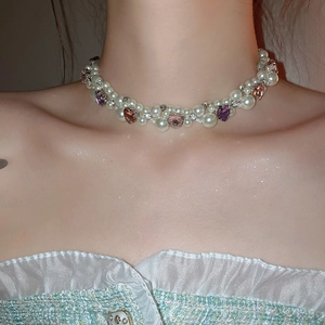 Close-up of double-strand pearl necklace with pink and purple crystal heart pendants