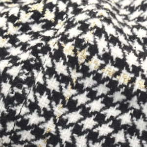 Nahaufnahme von schwarz-weißem Hahnentritt-Tweed mit schimmernden goldenen Metallfäden
