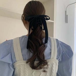 Elegant black velvet bow hair claw clip styled on woman's half-up hair back view