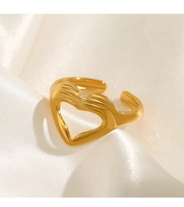 Vue détaillée de la bague en forme de cœur doré sur un tissu de satin beige